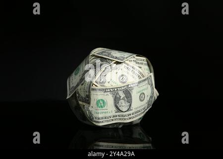 Sfera fatta di dollari su superficie a specchio nera Foto Stock