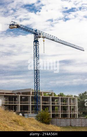 Gru a torre in un cantiere. Tre piani di un edificio incompiuto. Foto Stock