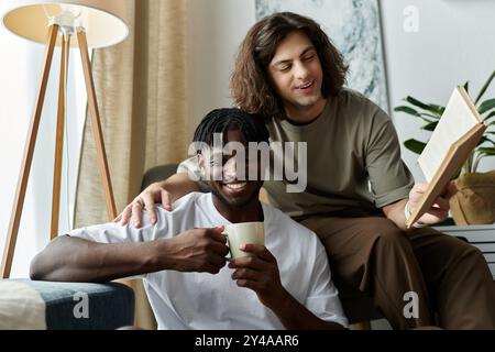 Una coppia gioiosa condivide risate e calore a casa, gustando un caffè e leggendo insieme. Foto Stock