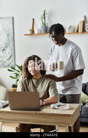 Una coppia allegra condivide i momenti a casa mentre un partner lavora al notebook. Foto Stock