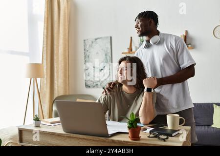 Due partner condividono un momento di amore mentre lavorano insieme nel loro luminoso ufficio domestico. Foto Stock