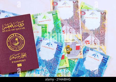 Passaporto dello stato del Qatar con banconote del Qatar, riyal in contanti vari nominali Foto Stock