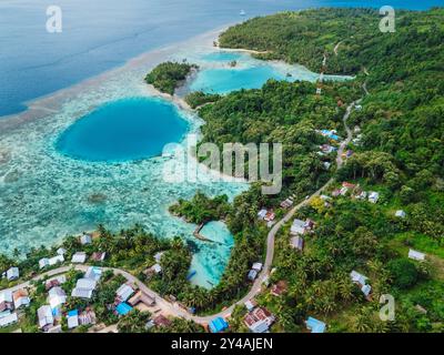 Costa marina con buco blu nella grande laguna e villaggio, paesaggio panoramico in Indonesia. Vista aerea Foto Stock