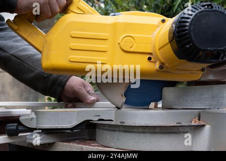 Carpenter taglia una spranga ad angolo con una sega circolare a croce, ideale per la costruzione in interni con visualizzazione della linea di taglio Foto Stock
