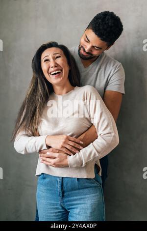 La bella coppia multietnica passa del tempo insieme, abbracciando e sorridendo Foto Stock