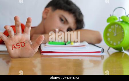 ASD, disturbo dello spettro autistico, palmo della mano del bambino con libri e quaderni e gesto di preoccupazione e tristezza Foto Stock