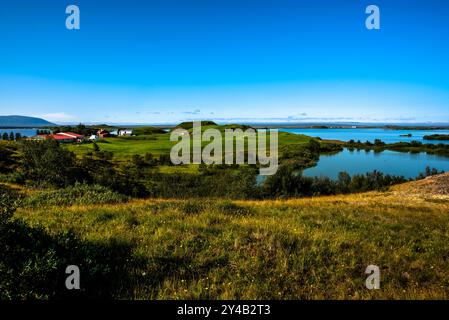 Lago vulcanico Myvatn con riflessi e isole, prati verdi e cieli blu nel nord dell'Islanda Foto Stock