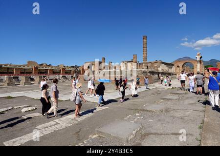 I turisti esplorano le antiche rovine di Pompei, in Italia, con cieli azzurri che evidenziano l'architettura storica e il Vesuvio in lontananza Foto Stock