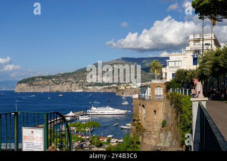 Una vista panoramica sulla costa da Sorrento, con scogliere, barche e un uomo che guarda la tranquilla costa mediterranea Foto Stock
