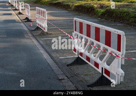 Le barriere stradali e il nastro di avvertenza bloccano una sezione di un'area di parcheggio, indicando che il locale è chiuso per lavori di costruzione o manutenzione. Foto Stock