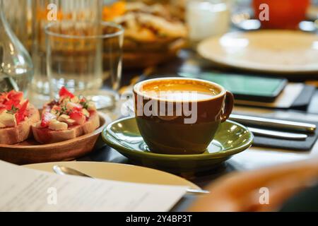 Tazza di caffè. Tavolo per la colazione in un ristorante. C'erano molti piatti, pane e caffè. Workshop di lavoro mattutino. Telefono cellulare. Foto Stock