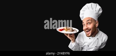 Excited Chef Holding Piatto Di Pollo In Piedi Su Sfondo Nero, Panorama Foto Stock