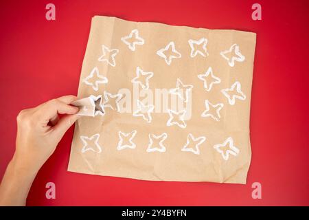 Attività facile per i bambini, come realizzare carta da imballaggio personalizzata, carta marrone con motivi bianchi, rotolo di carta igienica piegato, nastro rosso, esclusivo tessuto Foto Stock