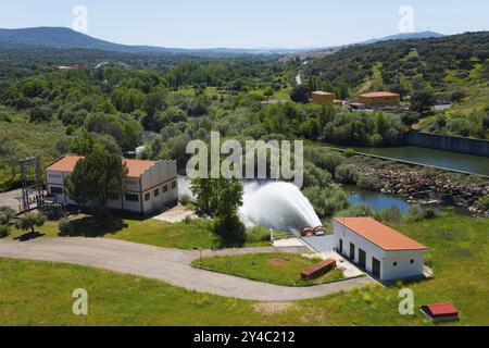 Edificio in un ambiente verde con un grande flusso d'acqua che scorre da un serbatoio, il serbatoio di Embalse de Plasencia, Embalse de Jerte, Rio Jerte, plase Foto Stock