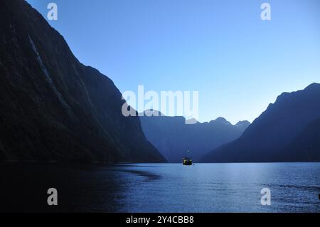 Alba nel fiordo di Milford Sound in nuova Zelanda con barca turistica Foto Stock