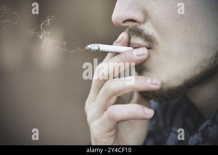 Uomo che fuma sigaretta da vicino di una sigaretta che fuma Foto Stock