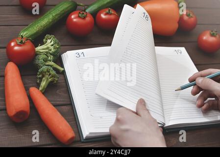 Concetto di dieta con uno smartphone, un blocco note e una penna circondati da un sacco di verdure salutari Foto Stock