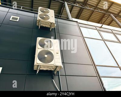 Unità di aria condizionata industriali montate su un moderno edificio in vetro e acciaio Foto Stock