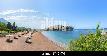 Panorama di Sveti Stefan e spiaggia sabbiosa sul mare Adriatico nelle soleggiate giornate estive, Montenegro, Europa Foto Stock