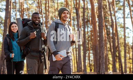 Tre allegri amici multirazziali che camminano nella foresta Foto Stock