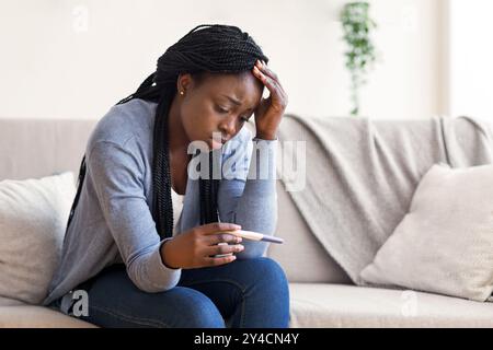 Premuto nero ragazza azienda test di gravidanza, sconvolto con esito positivo Foto Stock