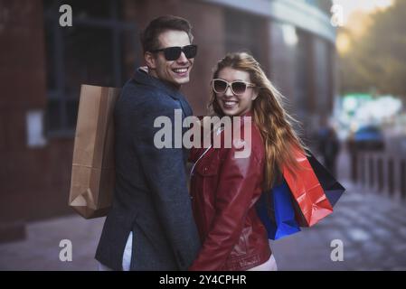 Immagine che mostra lo shopping di una giovane coppia in città. Ritratto di una coppia con borse della spesa in città. Concetto di persone, vendita, amore e felicità Foto Stock