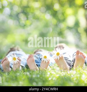 Famiglia con fiori a margherita adagiati su erba verde su sfondo sfocato primaverile Foto Stock