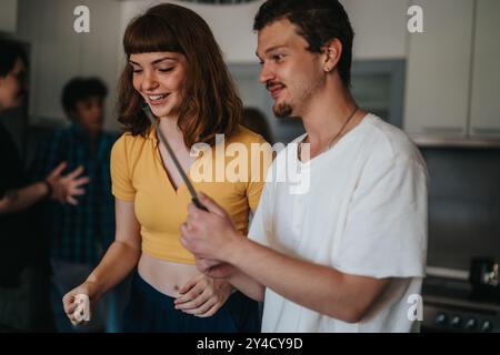 Giovani amici che si divertono in cucina con una divertente sessione di cucina Foto Stock