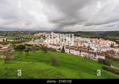 Le nuvole di tempesta si radunano sopra un'estesa città portoghese, annidata tra verdi colline. Foto Stock