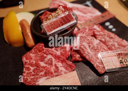 Vista ravvicinata di una selezione premium di fette di manzo Wagyu crude, preparate per la cottura alla griglia. Foto Stock