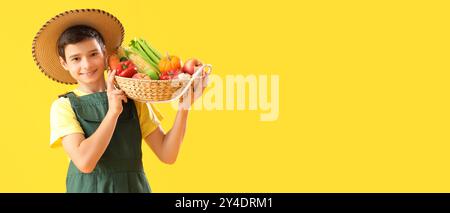 Piccolo agricoltore che tiene un cestino di frutta e verdura fresca su sfondo giallo con spazio per il testo Foto Stock