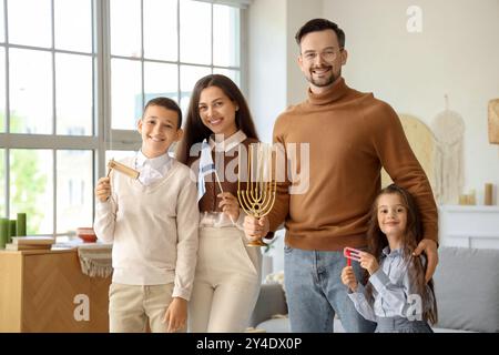 Felice famiglia ebrea con battiti, menorah e bandiera di Israele a casa Foto Stock