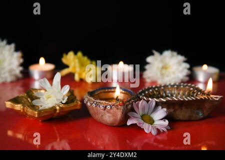 Lampade Diya con splendidi fiori e candele accese su sfondo colorato. Festa dei Divaly Foto Stock