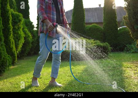 Uomo che innaffiava erba verde sul prato nel cortile, primo piano Foto Stock