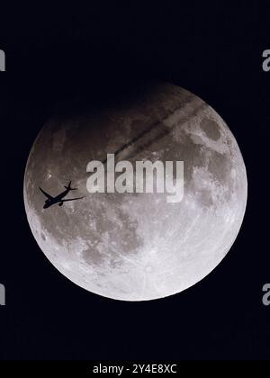 Monroe, Wisconsin, Stati Uniti. 17 settembre 2024. Un volo TAP Air Portugal (TAP238) da San Francisco a Lisbona vola di fronte alla Super Moon parzialmente eclissata, vista da terra a Monroe, Wisconsin, il 17 settembre 2024. Questa eclissi lunare coincise con la Luna di Corn, nota anche come la Luna di Harvest, creando un raro evento celeste visibile in alcune parti del mondo. La silhouette dell'aereo che attraversa la luna scintillante offre un contrasto sorprendente tra aviazione e astronomia. (Credit Image: © Ross Harried/ZUMA Press Wire) SOLO PER USO EDITORIALE! Non per USO commerciale! Foto Stock