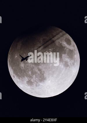 Monroe, Wisconsin, Stati Uniti. 17 settembre 2024. Un volo TAP Air Portugal (TAP238) da San Francisco a Lisbona vola di fronte alla Super Moon parzialmente eclissata, vista da terra a Monroe, Wisconsin, il 17 settembre 2024. Questa eclissi lunare coincise con la Luna di Corn, nota anche come la Luna di Harvest, creando un raro evento celeste visibile in alcune parti del mondo. La silhouette dell'aereo che attraversa la luna scintillante offre un contrasto sorprendente tra aviazione e astronomia. (Credit Image: © Ross Harried/ZUMA Press Wire) SOLO PER USO EDITORIALE! Non per USO commerciale! Foto Stock