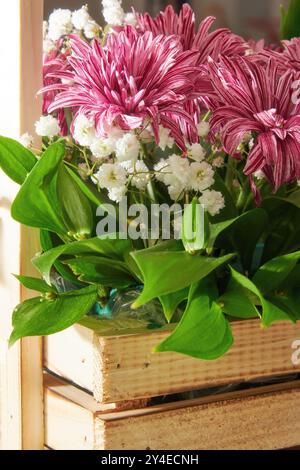 Fiori rosa e bianchi disposti in una scatola di legno con foglie verdi. Decorazione astratta degli interni della casa di erbe Foto Stock