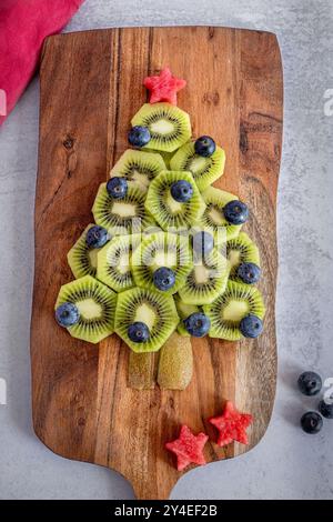Albero di Natale con frutta kiwi, mirtilli e anguria su un piatto di legno Foto Stock