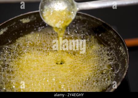 Bollicine di Ghee calde e sobbollenti in una padella, pronte per la cottura. Foto Stock