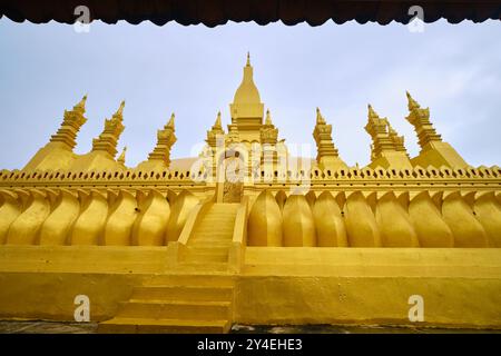 Una vista del famoso stupa d'oro, punto di riferimento, in un giorno torbido, grigio, lunatico e mistico. A Pha That Luang a Vientiane, Laos. Foto Stock