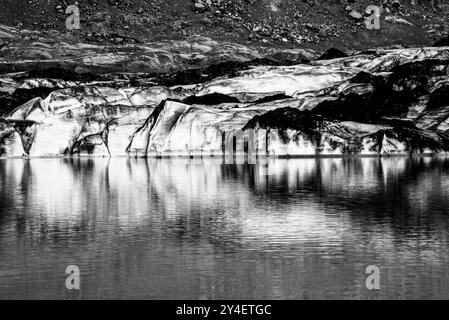 Il ghiacciaio di Solheimajokull era coperto di fuliggine dalle eruzioni precedenti con il lago glaciale che scendeva dal vulcano vicino a Vik in Islanda Foto Stock