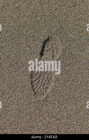 Primo piano delle impronte di stivali in sabbia soffice sulla spiaggia. Foto Stock