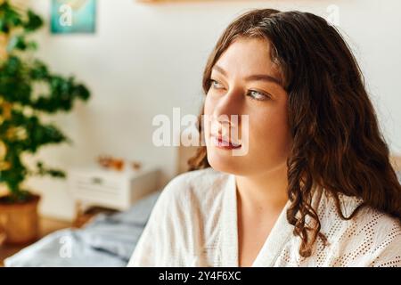 Una giovane donna di grandi dimensioni si rilassa a casa, perduta nel pensiero e godendo della sua atmosfera accogliente. Foto Stock