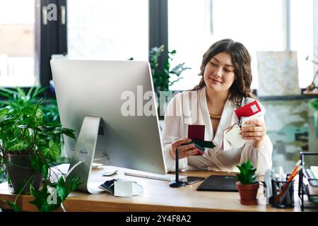 La donna è seduta alla sua scrivania, impegnata nella creazione di scatole colorate e decorazioni vivaci. Foto Stock