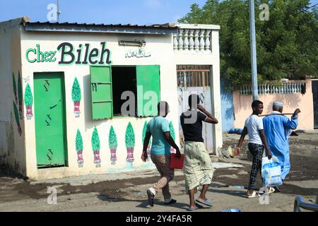 Gibuti: Gruppo di uomini che passano accanto al negozio di un venditore di khat. Il commercio di khat e il suo consumo sono costantemente in aumento, e sono diventati un grande pub Foto Stock