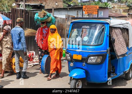 Gibuti: Atmosfera nella città vecchia, donne in abito tradizionale nel mezzo del traffico con un risciò Bajaj auto, mezzi di trasporto locali. Ve Foto Stock