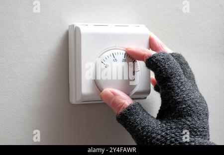 un addetto anziano abbassa il termostato per risparmiare denaro Foto Stock