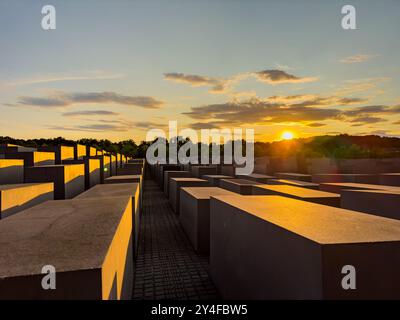 Famoso Memoriale ebraico dell'Olocausto vicino alla porta di Brandeburgo, con luce dorata serale e cielo blu al tramonto in estate a Berlino. Foto Stock