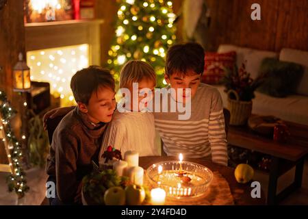 Tre bambini, accensione delle candele in poche parole, tradizioni natalizie ceche, stanza decorata, tradizioni familiari Foto Stock