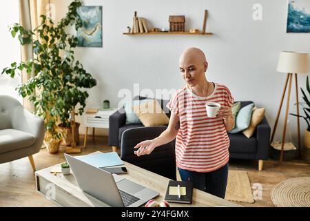 La luce del sole scorre in una stanza accogliente mentre una giovane donna sorseggia un caffè e usa il suo laptop. Foto Stock